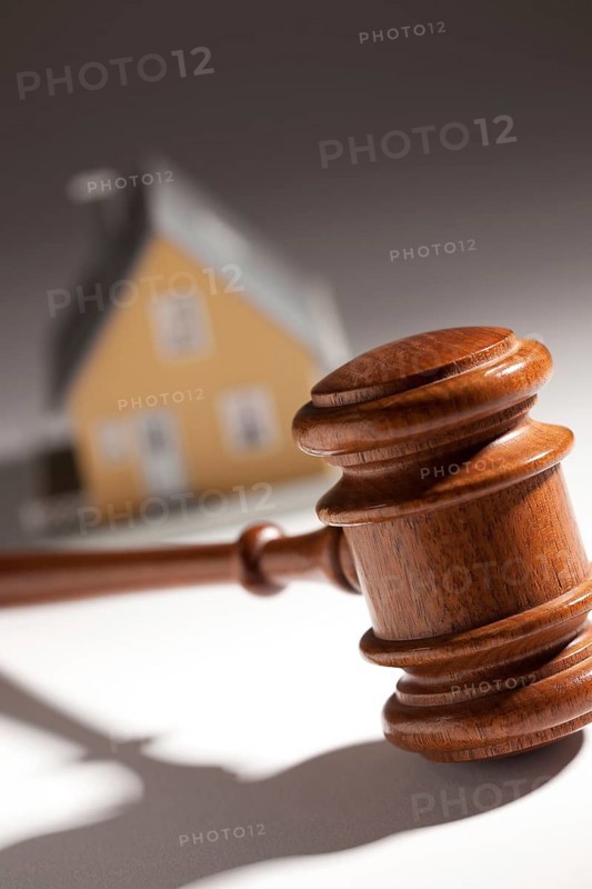 Gavel and model home on gradated background with selective focus