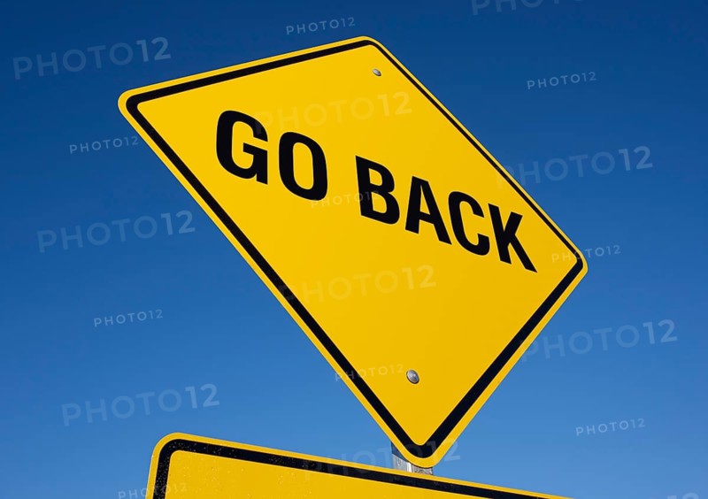 Go back yellow road sign against a deep blue sky with clipping path