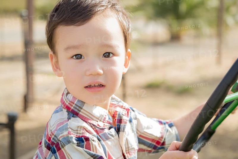 Adorable mixed-race young boy playing on the tractor at the pumpkin patch