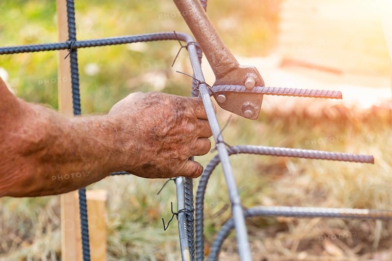 Worker using tools to bend steel rebar at construction site
