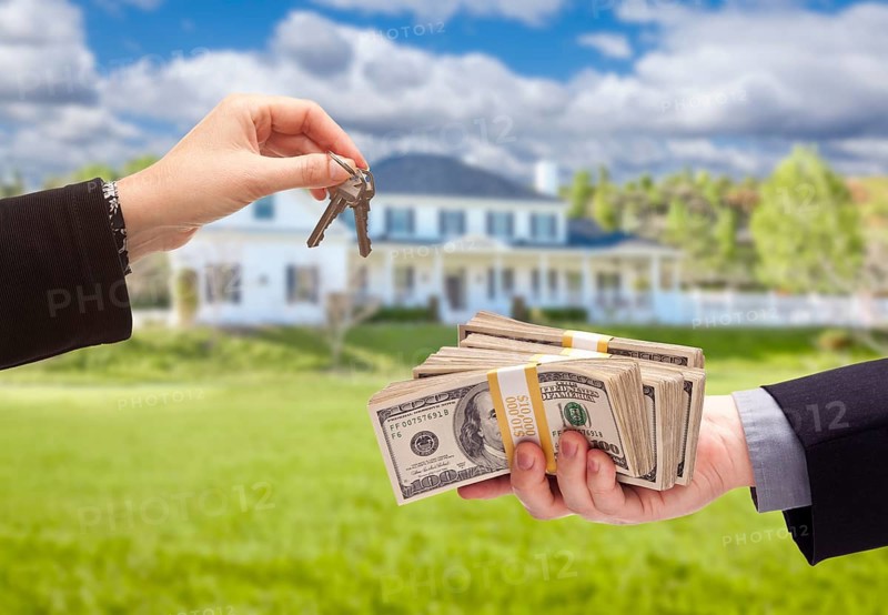 Handing over cash for house keys in front of beautiful new home