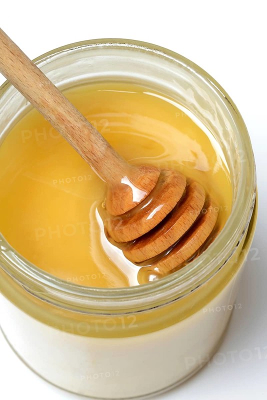 Cremiger Bienenhonig in Glas und Honigloeffel