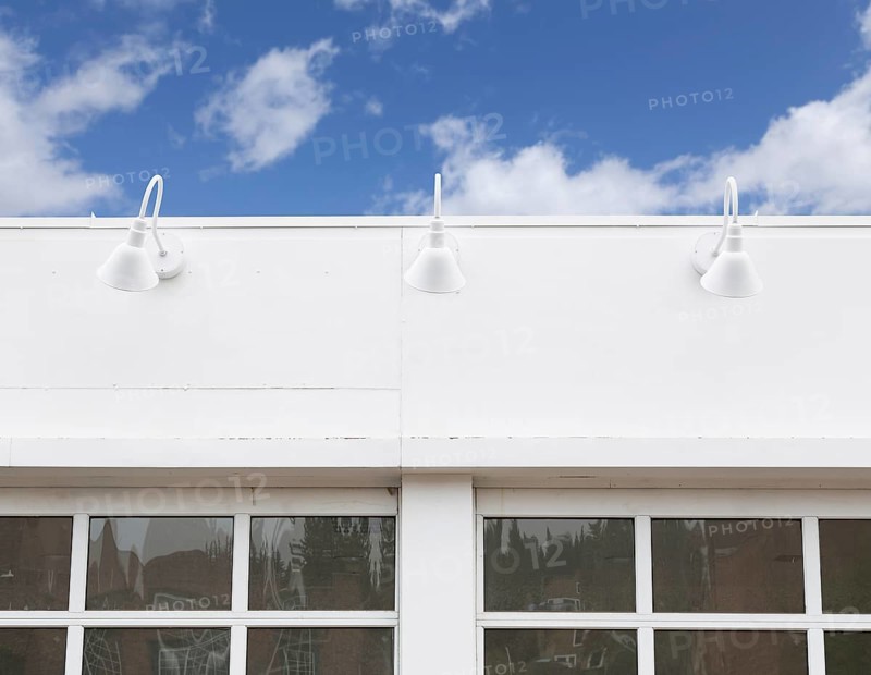 Blank building front with lamps and windows against blue sky