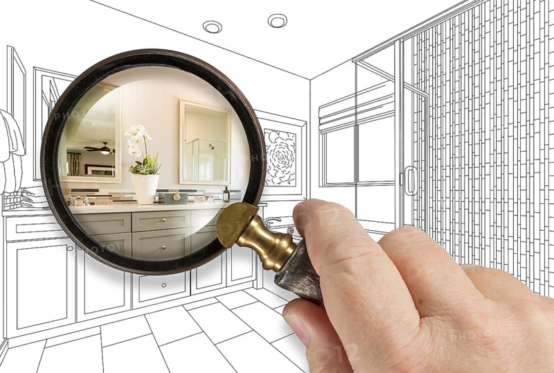 Hand holding magnifying glass revealing custom bathroom design drawing and photo combination