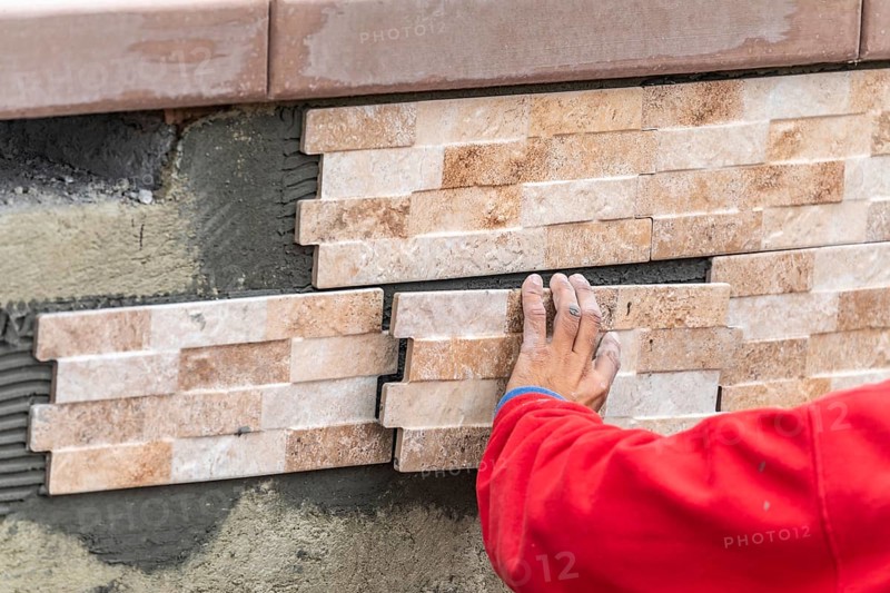 Worker installing wall tile at construction site
