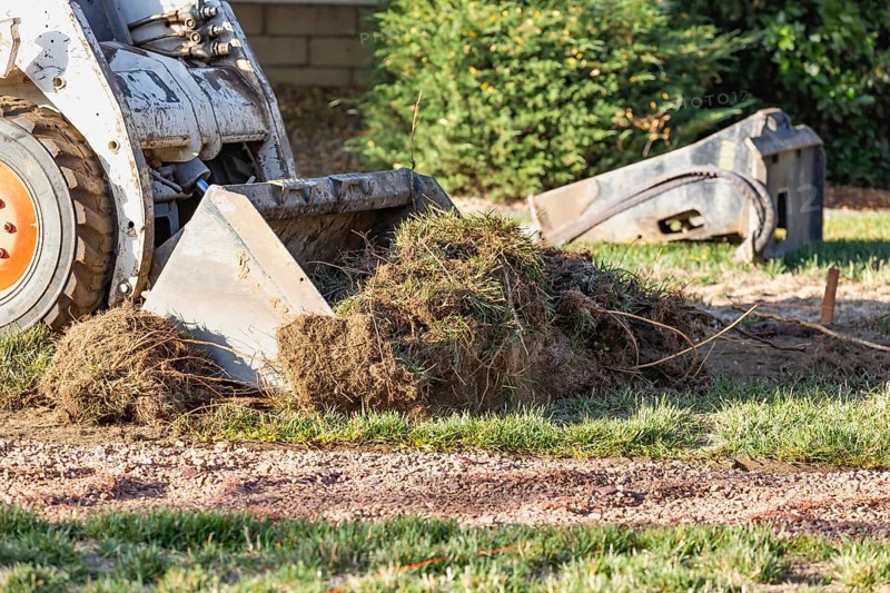 Small bulldozer removing grass from yard preparing for pool installation