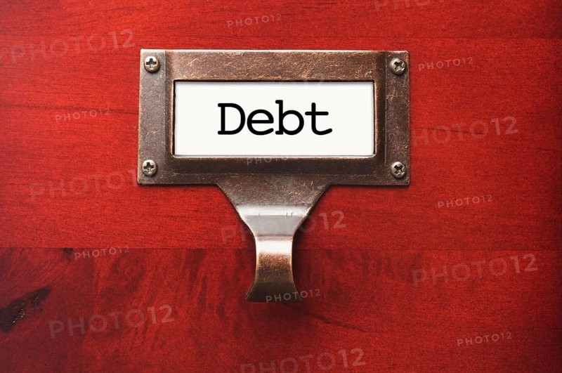 Lustrous wooden cabinet with debt file label in dramatic light