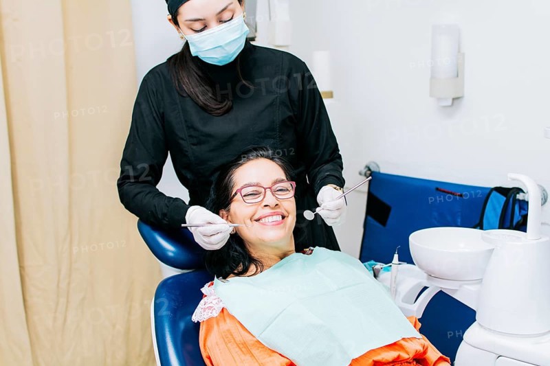 Dentist examining mouth to smiling patient