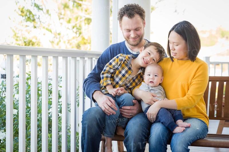 Young mixed-race chinese and caucasian family portrait on their front porch