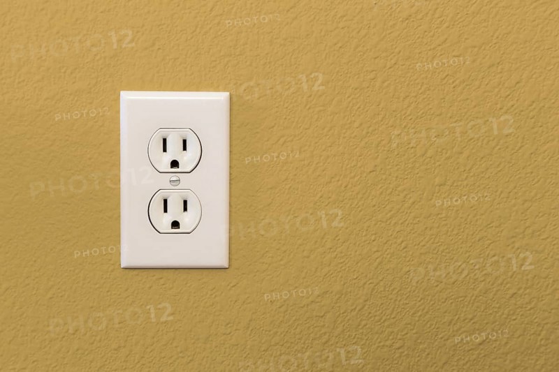 Electrical sockets in colorful mustard yellow wall of house