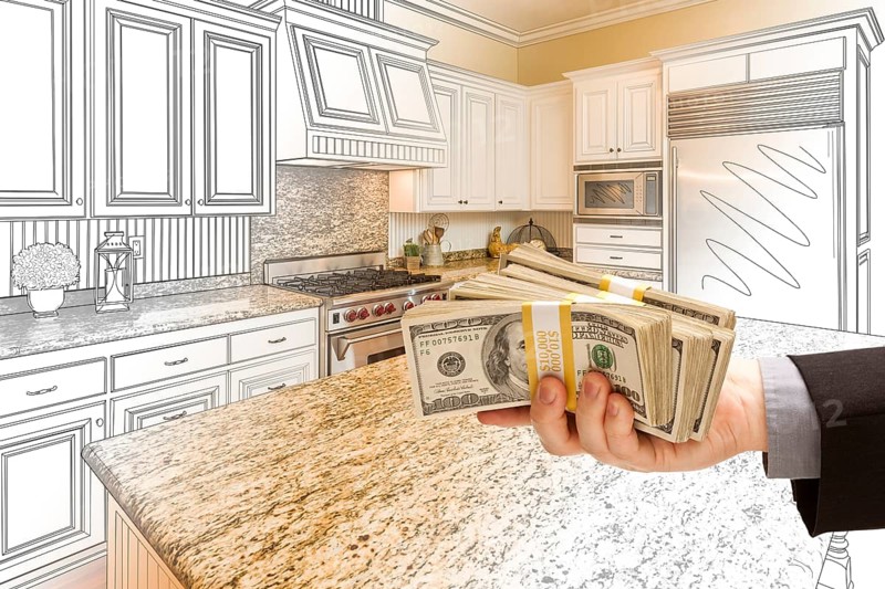 Hand handing stacks of money over custom kitchen design drawing and photo combination