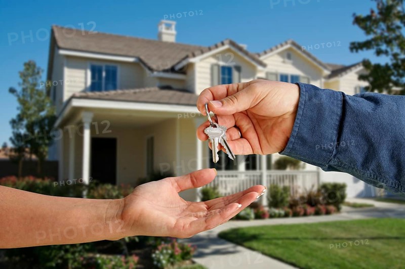 Handing over the house keys in front of a beautiful new home