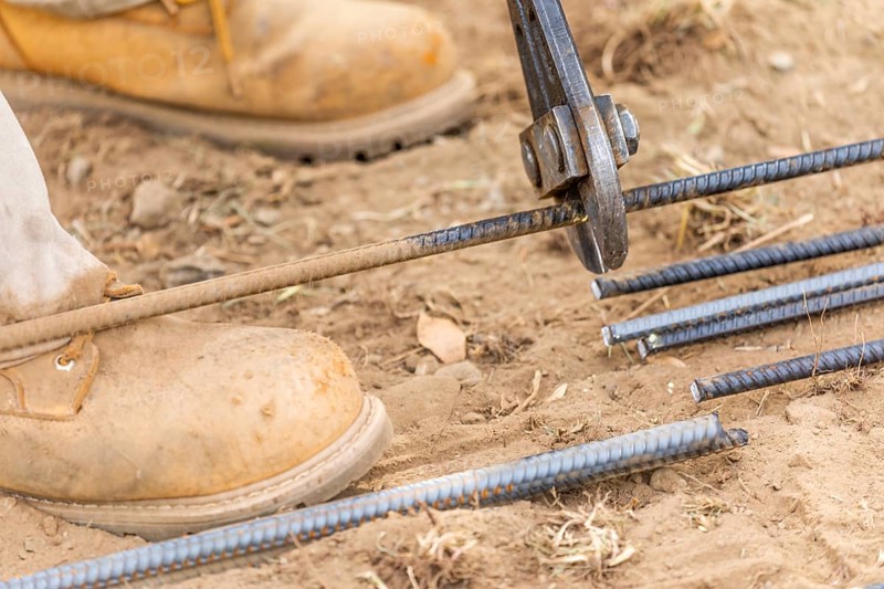 Worker cutting steel rebar at construction site abstract