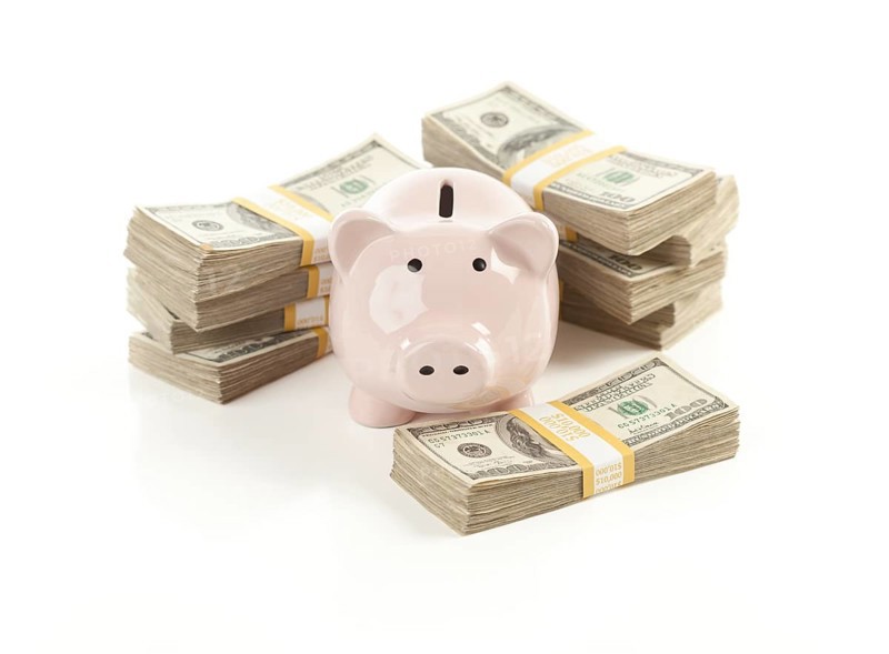 Pink piggy bank with stacks of hundreds of dollars isolated on a white background