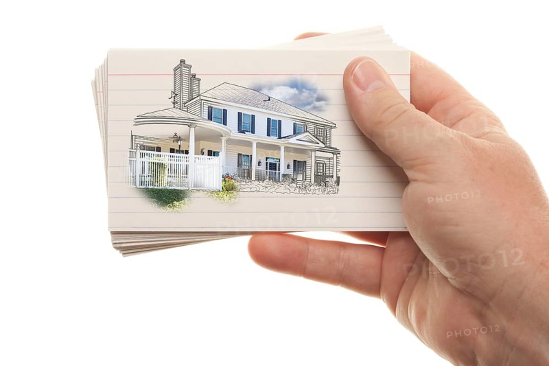 Male hand holding stack of flash cards with house drawing isolated on a white background