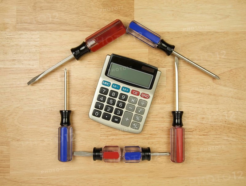 House shaped by screwdrivers and calculator on a wood background