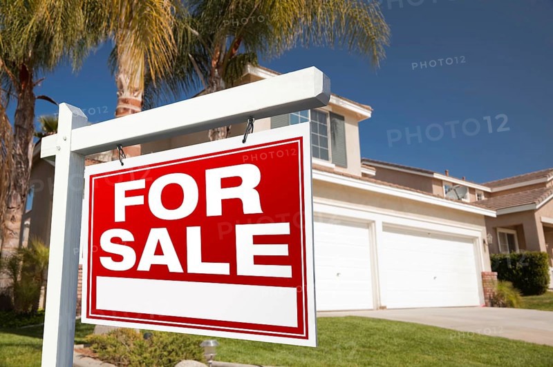 For sale real estate sign in front of house