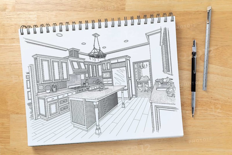 Sketch pad on desk top with drawing of custom kitchen interior next to engineering pencil and ruler scale