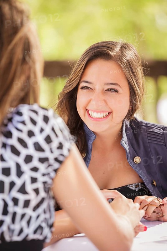 Two mixed-race girlfriends having A conversation at an outoor patio table