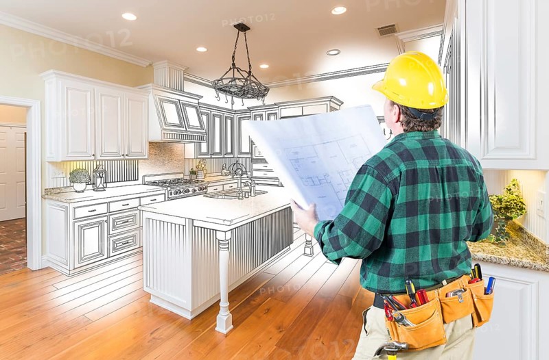 Male contractor with hard hat and plans looking at custom kitchen drawing photo combination on white