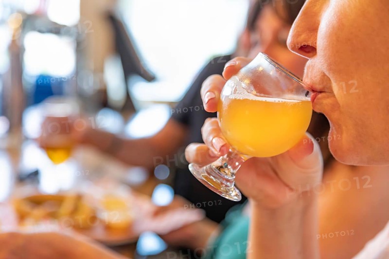 Female sipping glass of micro brew beer at bar with friends