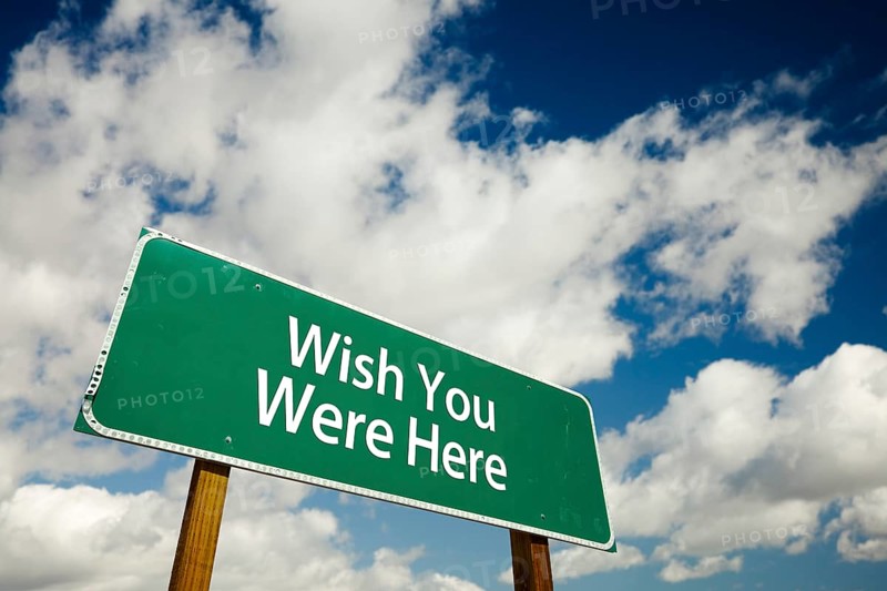 Wish you were here road sign with dramatic clouds and sky