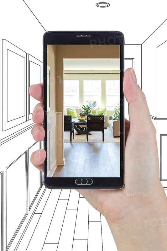 Hand holding smart phone displaying photo of the house hallway drawing behind