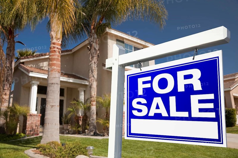 For sale real estate sign in front of house