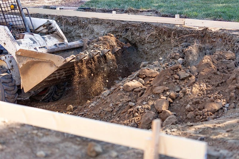 Small bulldozer digging in yard for pool installation