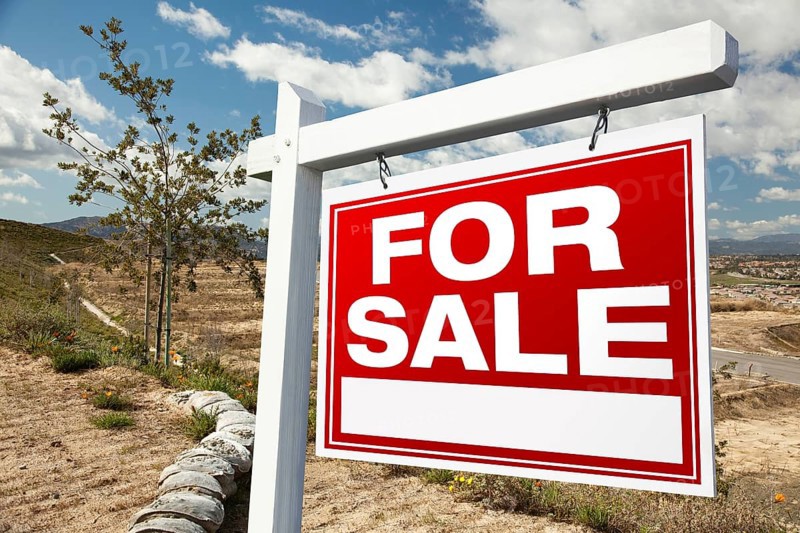 For sale real estate sign and emtpy construction lots