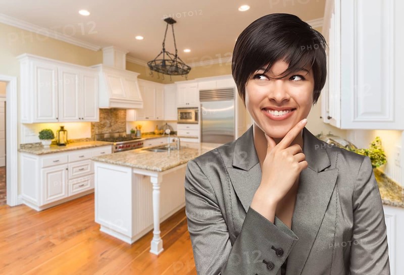 Pretty mixed-race woman looking back over shoulder inside custom kitchen interior