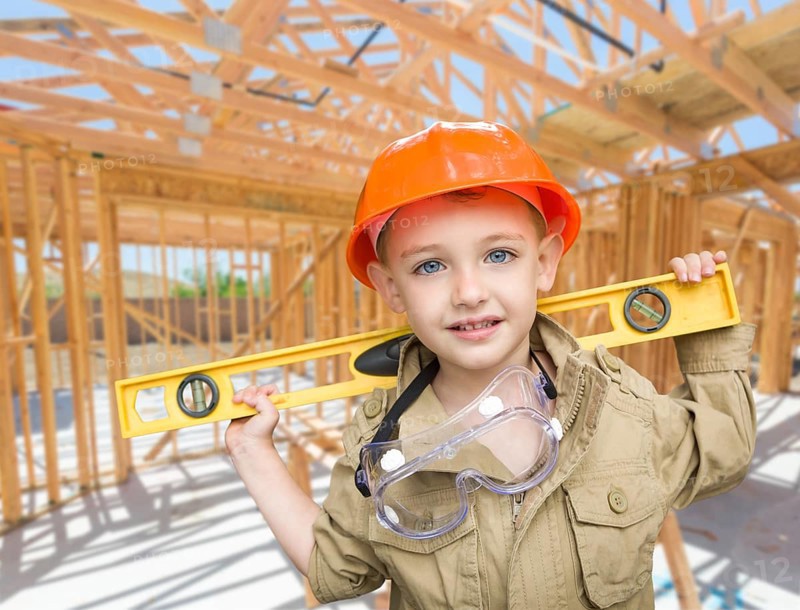 Young boy contractor with level on site inside new home construction framing