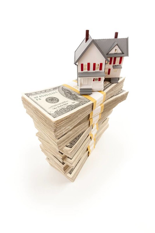 Small house on stacks of hundred dollar bills isolated on a white background