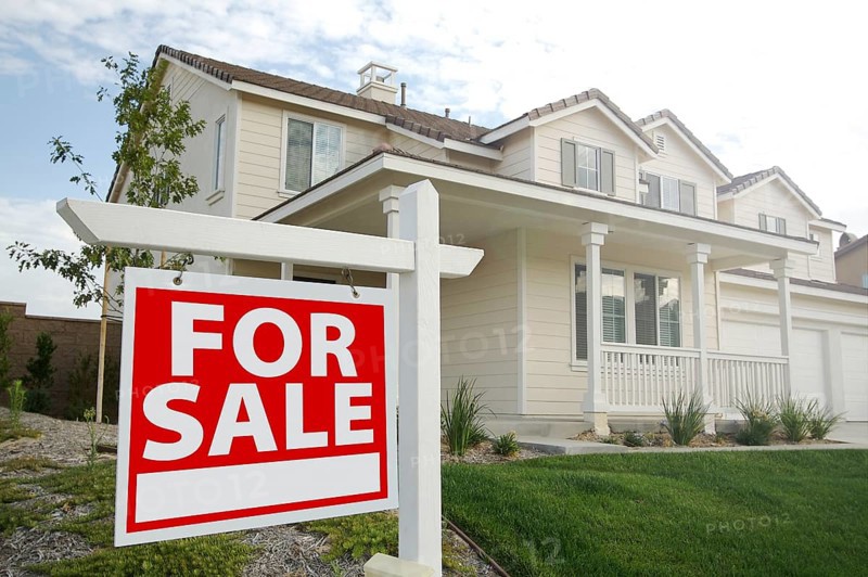 For sale real estate sign in front of beautiful new home