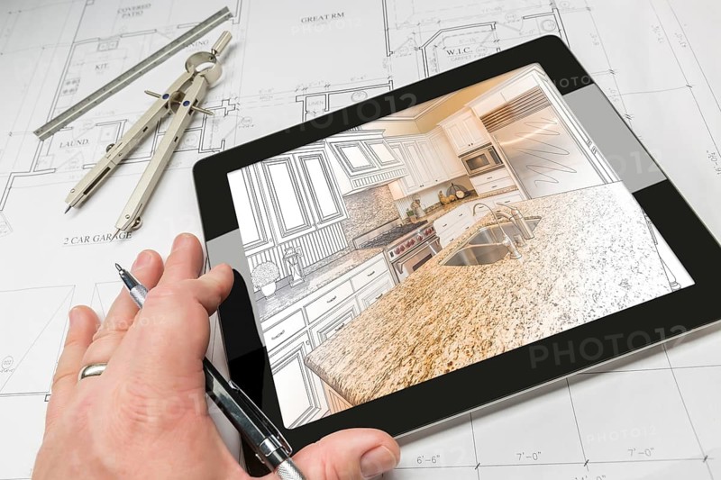 Hand of architect on computer tablet showing custom kitchen illustration photo combination over house plans