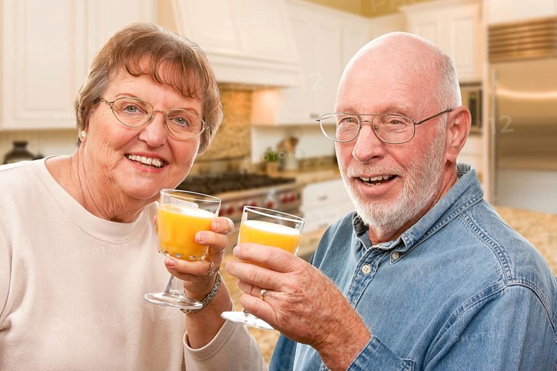 Happy senior couple with glasses of orange juice isolated on a white background