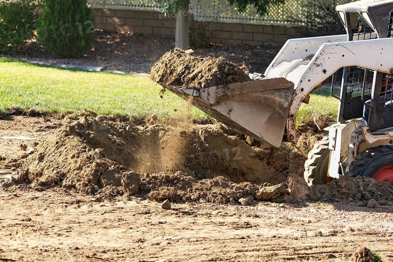 Small bulldozer digging in yard for pool installation