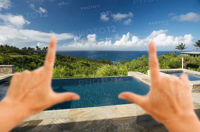 Hands framing pool and hot tub overlooking the ocean
