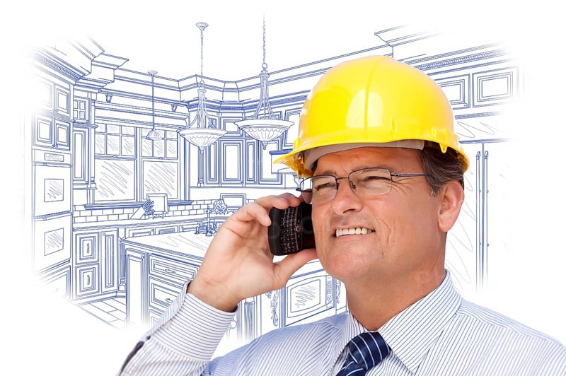 Contractor in hardhat on cell phone over custom kitchen drawing on white