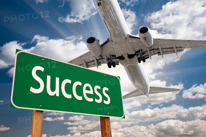 Success green road sign and airplane above with dramatic blue sky and clouds