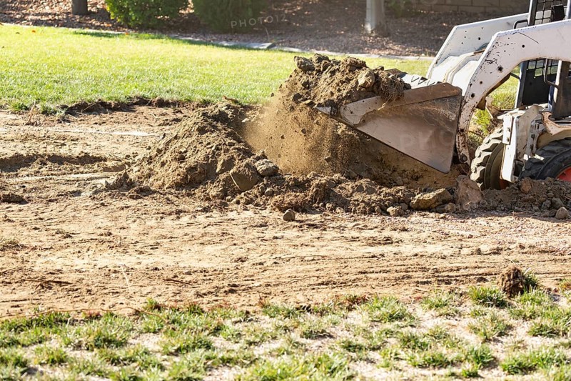 Small bulldozer digging in yard for pool installation