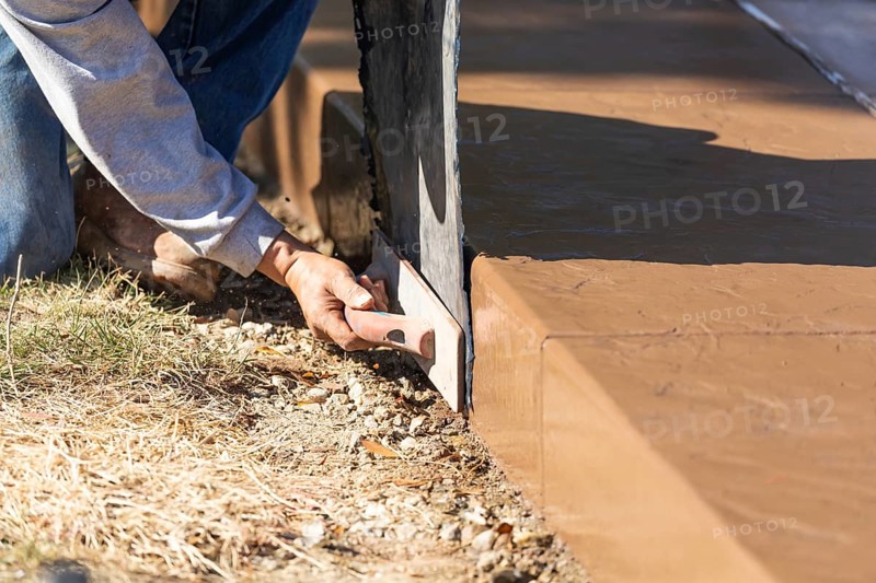 Construction worker applying pressure to texture template on wet cement