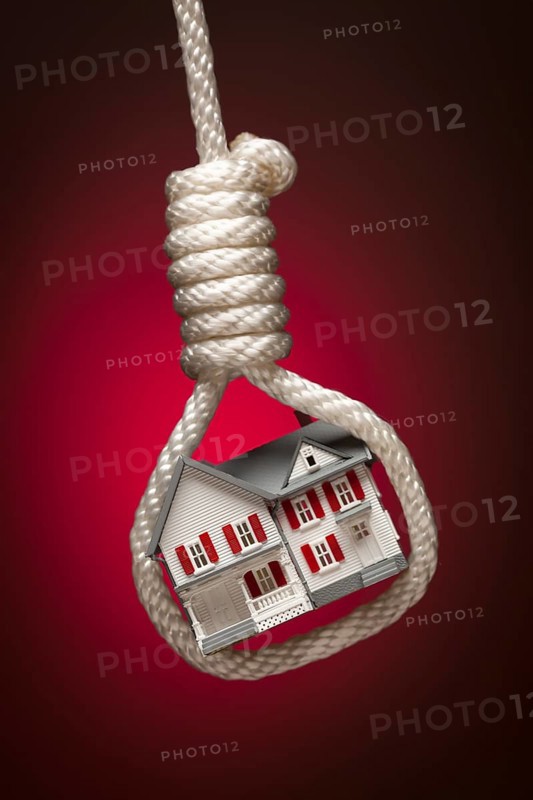 House tied up and hanging in hangman's noose on red spot lit background