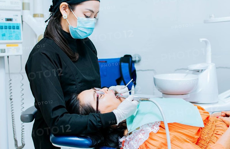 The stomatologist cleaning a patient's teeth