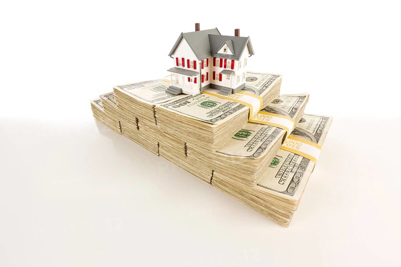 Stacks of one hundred dollar bills with small house on slight gradation
