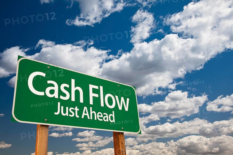 Cash flow green road sign over dramatic clouds and sky