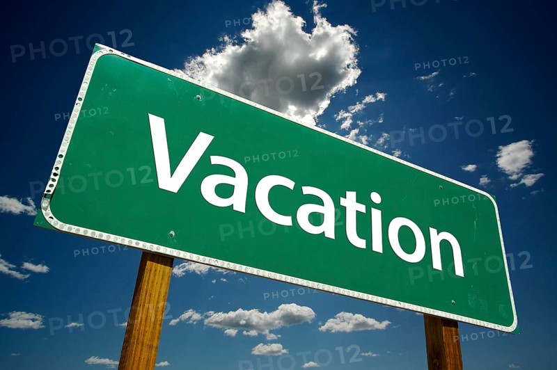 Vacation green road sign over dramatic blue sky and clouds with clipping path