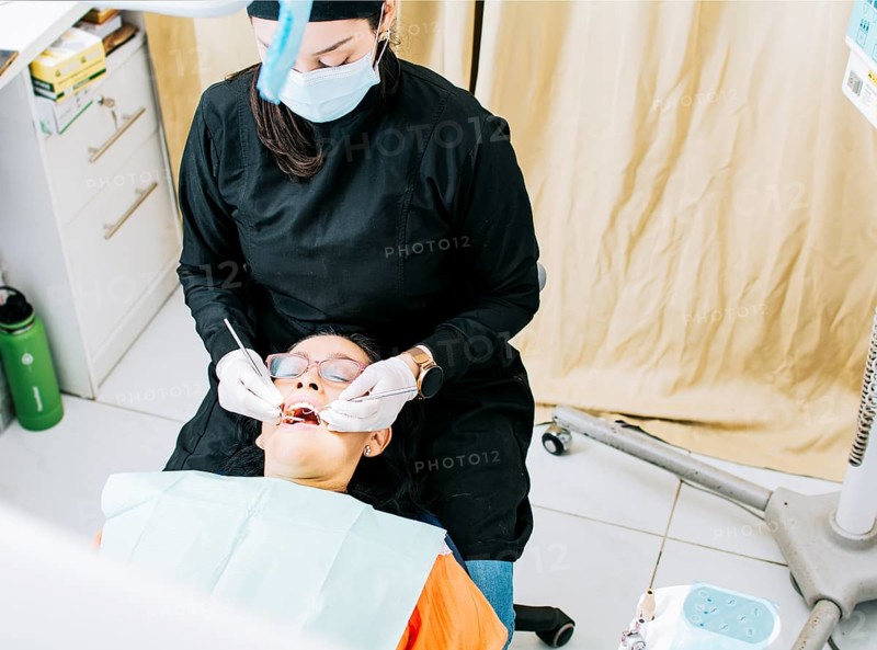 Woman dentist doing endodontics to woman patient.  Dentist with patient lying down. Dentist examining mouth to patient. Dentist performing stomatology