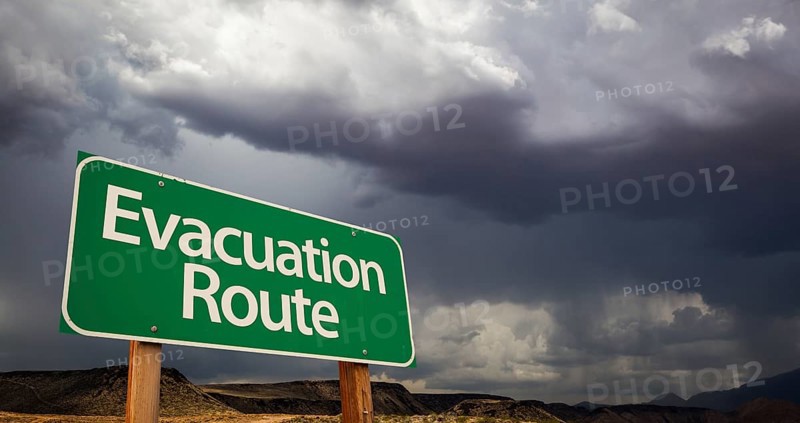 Evacuation route green road sign with dramatic clouds and rain