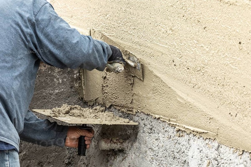 Tile worker applying cement with trowel at pool construction site
